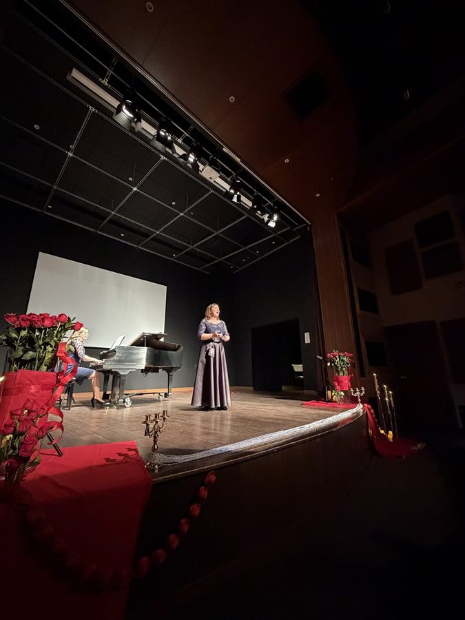 Olena Simsek performing on stage with piano accompaniment